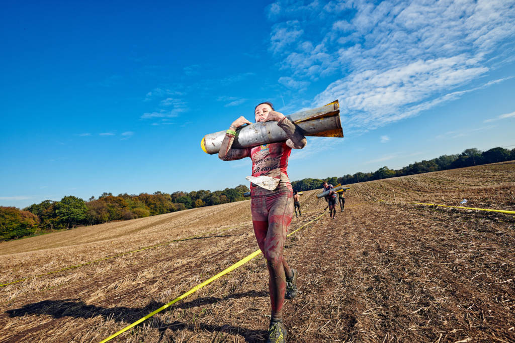 Man carrying object through obstacle course race racing with integrity.