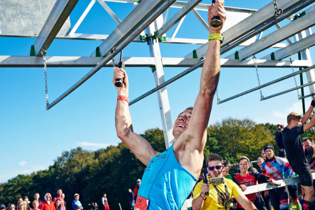 A man hanging on an obstacle in an obstacle course race