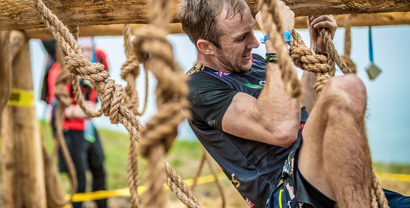 Male athlete going through rope obstacle